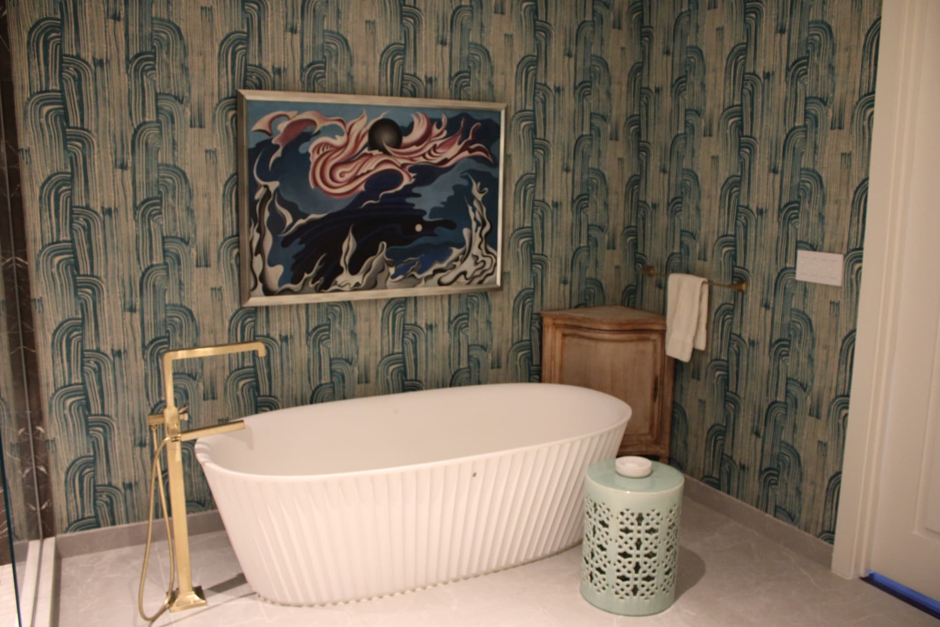 Fluted freestanding tub with a brass floor-mounted faucet beneath an abstract painting — Downtown Nashville, Nashville
